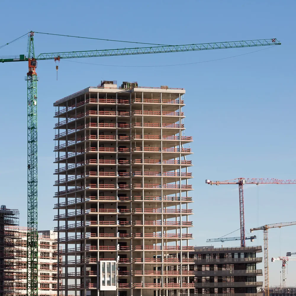 Rohbauten unter Kränen vor blauem Himmel