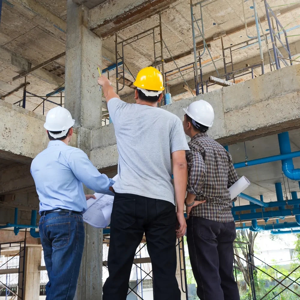 Bauingenieure mit Helmen besprechen sich in einem Rohbau